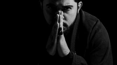 A black and white photo of a man covering his face